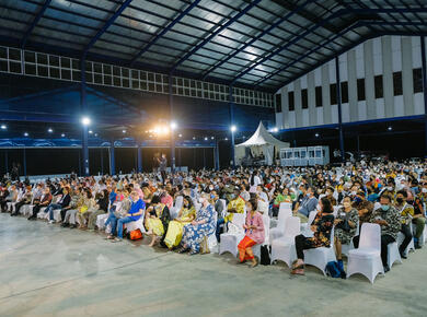 crowd in colourful clothing in a large open-walled building