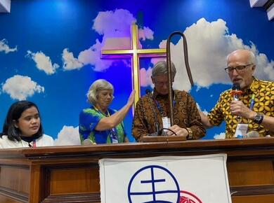 a man and a woman lay hands in prayer on a man in the middle while a second woman looks on