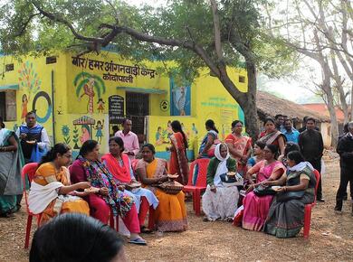 women dressed in bright colours sit outdoors sharing a meal